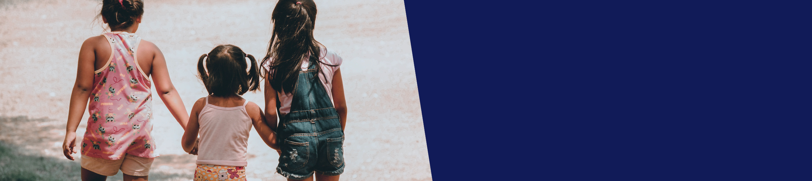 Three children holding hands by a river