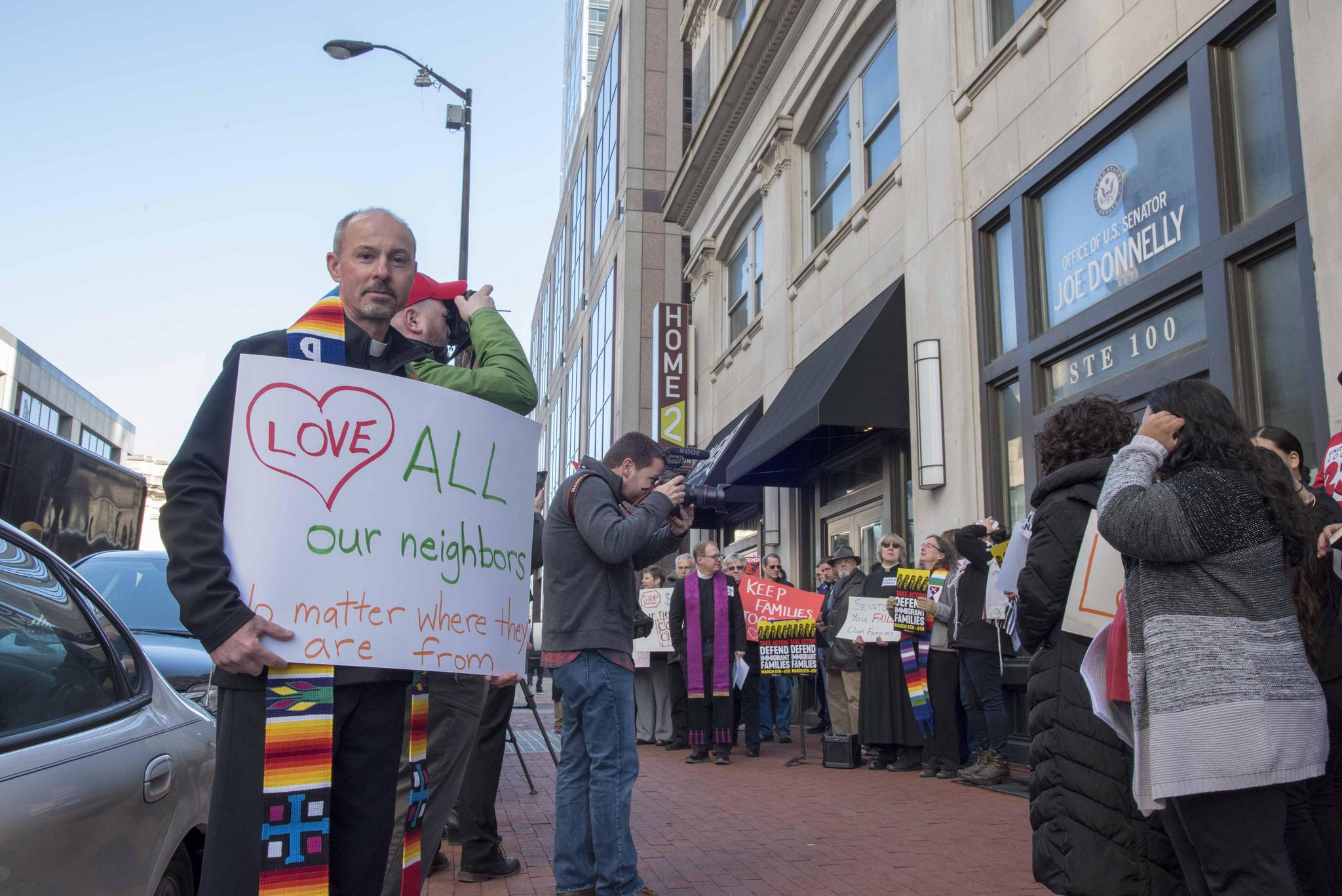 A protester holding a sign looks at the camera.