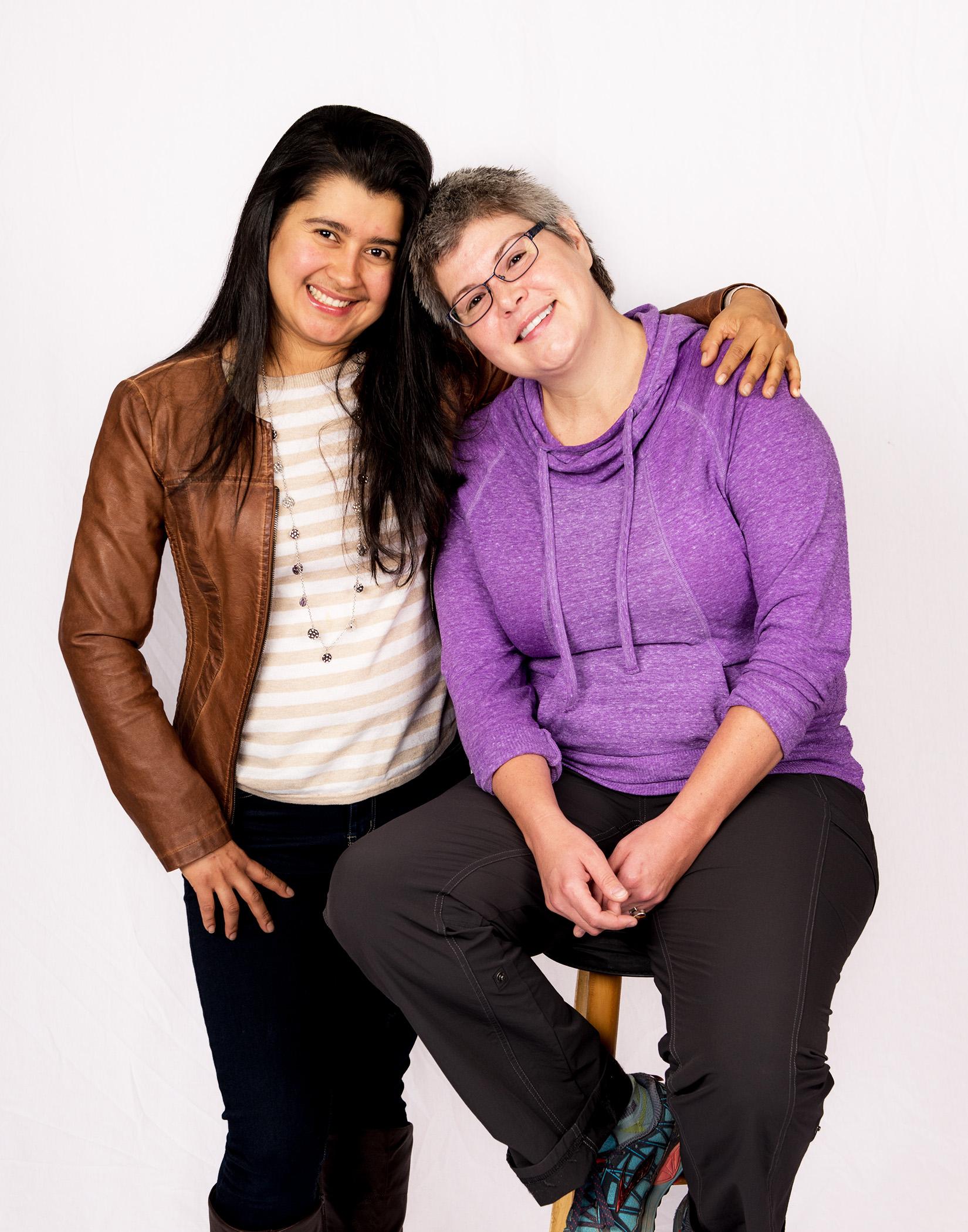 Two women hug while posing for the camera.