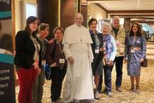 Attendees at the 2019 convening stand next to a image of Pope Francis.