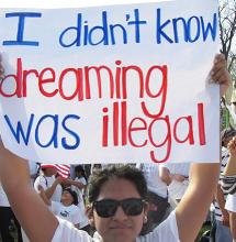 A person holding up a sign that reads "I didn't know dreaming was illegal."