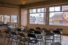 An empty room with chairs facing a window.