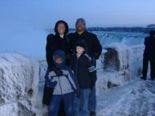A family of four stands in front of Niagara Falls.
