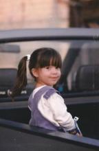 A young girl smiles at the camera from the back of a pickup truck.