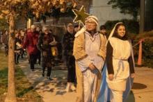 A group of people in historical clothing walk down the street.