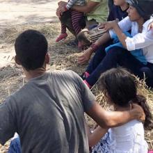 People sitting in the shade with their children