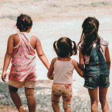 Three children holding hands by a river