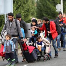 A picture of people in a formed line carrying luggage.